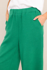 Close up view of these pants that feature a high waisted design, an elastic waistband, functional hip pockets, a textured crisscross design, and a wide leg.