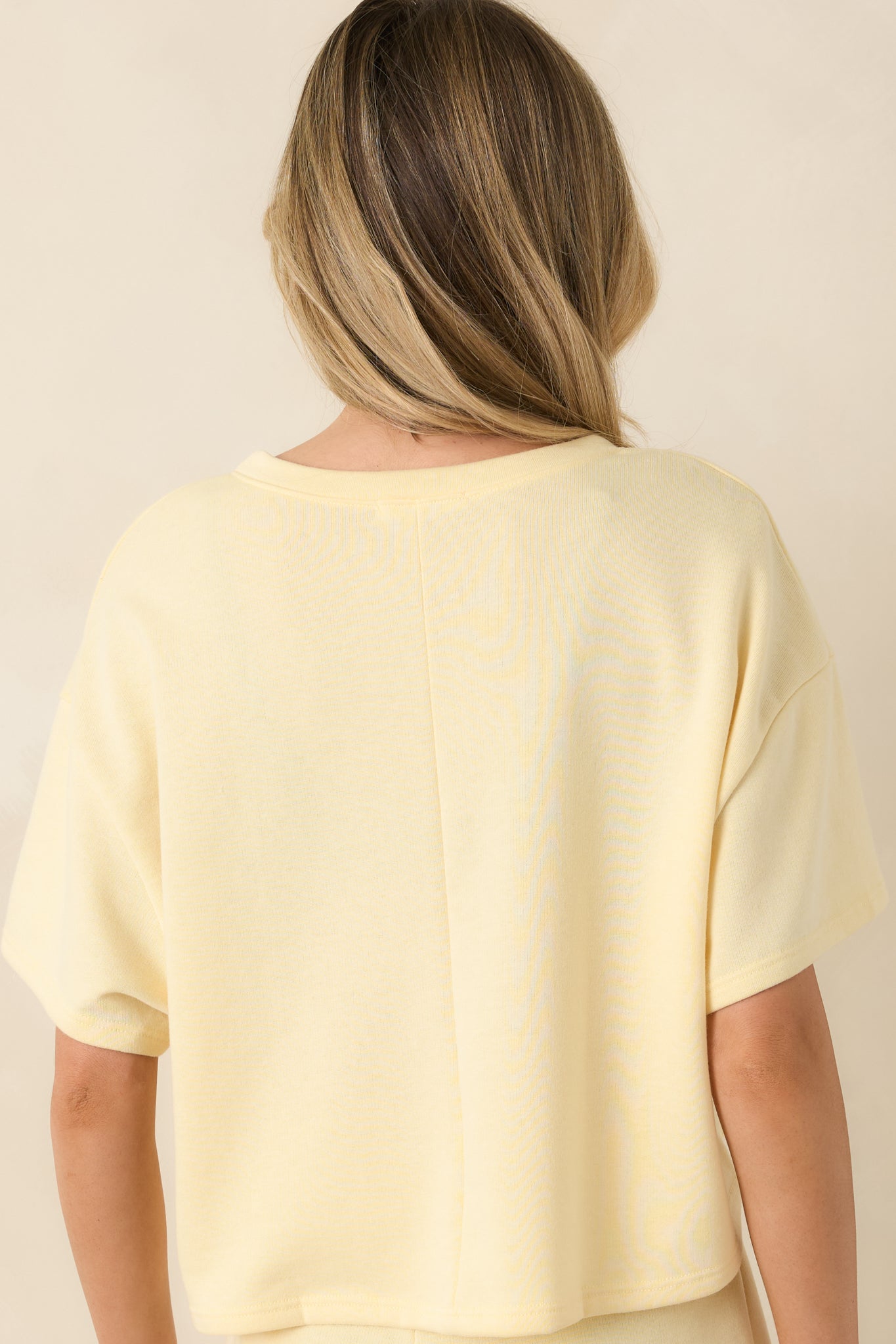 Rear view of the banana yellow cropped tee featuring a relaxed silhouette and smooth lightweight knit finish.