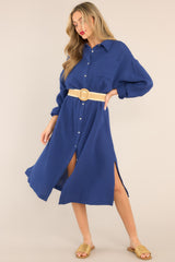 This Navy Gauze Midi Dress features a collared neckline, functional buttons down the front, a front pocket on the left side of the bust, long sleeves with a cuff secured by a functional button, and two slits up the bottom hemline ending just below the knee.
