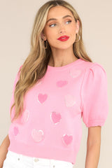 Front view of this top that features a crew neckline, textured hearts with sequin detailing, puffed sleeves, and a ribbed hemline. 