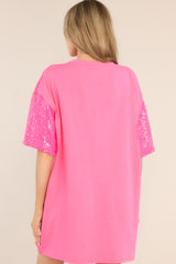 Back view of this tunic that features a round neckline, short sleeves, functional waist pockets, a jersey-style silhouette, colorful sequins throughout, and a fun heart pattern.