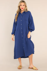 Front view of this Navy Gauze Midi Dress featuring a collared neckline, functional buttons down the front, a front pocket on the left side of the bust, long sleeves with a cuff secured by a functional button, and two slits up the bottom hemline ending just below the knee.