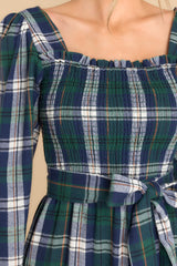 Close up view of this dress that features a square neckline, long sleeves with elastic cuffs, a fully smocked bust section, and a self-tie belt at the waist.
