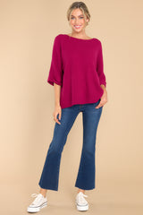 This all magenta colored top features a round neckline, quarter sleeves with cuffed arms, and a chunky knit material. 