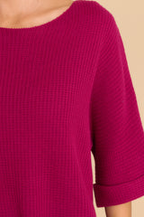 Close up view of this top that features a round neckline, quarter sleeves with cuffed arms, and a chunky knit material. 