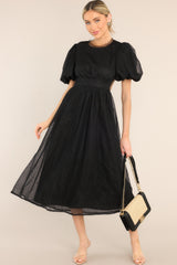 Full body view of this midi dress that features a round tulle neckline, short puff sleeves, an open back with a four button closure, and a tulle flowy skirt.