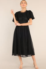 Front view of this midi dress that features a round tulle neckline, short puff sleeves, an open back with a four button closure, and a tulle flowy skirt.