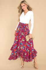 Full body view of this maxi skirt that doubles as a strapless dress with smocked side panels, an adjustable self-tie bow around the waistband/bust, a flowy skirt, an uneven hemline, and a vibrant pattern throughout.