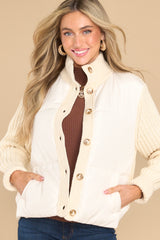 This ivory coat features a turtle neckline, functional buttons down the front, long knitted sleeves, and functional pockets.