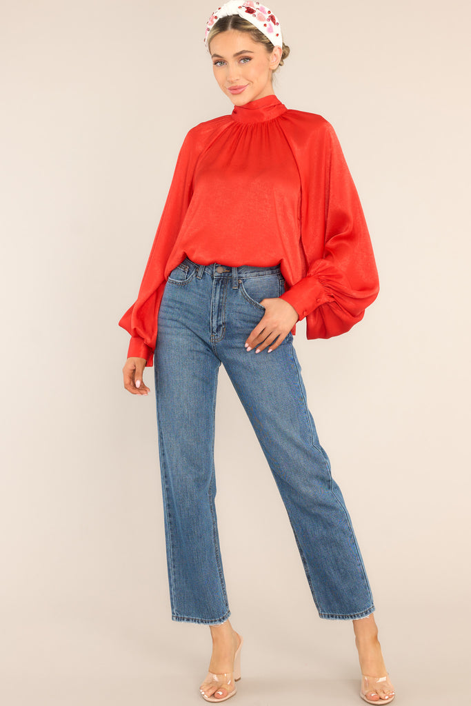 This all red top features a high neckline, balloon sleeves with buttons at the cuff, an adjustable self tie around the neck, and a flowy fit.