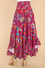 Back view of this maxi skirt that doubles as a strapless dress with smocked side panels, an adjustable self-tie bow around the waistband/bust, a flowy skirt, an uneven hemline, and a vibrant pattern throughout.