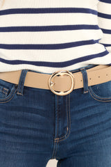 This beige belt features a circular buckle closure, and gold hardware.