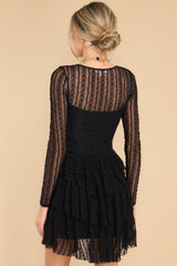 Back view of this dress that features detailed lace fabric throughout, a v-neckline, and sheer long sleeves.