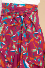 Close up view of this maxi skirt that doubles as a strapless dress with smocked side panels, an adjustable self-tie bow around the waistband/bust, a flowy skirt, an uneven hemline, and a vibrant pattern throughout.