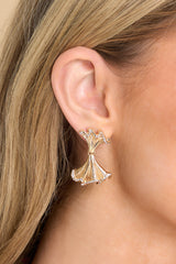 Model shown wearing earrings that feature gold hardware, small rhinestone detailing, and a secure post backing.