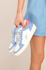 These white and blue sneakers feature a rounded toe, functional laces, medium wash denim trim, silver stars, and neon pink detailing.