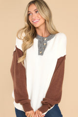 Front view of this sweater that showcases a grey neckline, creme bodice, and brown sleeves.