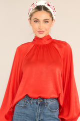 Front view of this top that features a high neckline, balloon sleeves with buttons at the cuff, an adjustable self tie around the neck, and a flowy fit.
