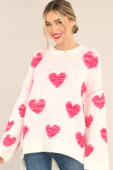 Front view of this sweater that showcases the pink heart pattern of the ivory fabric.