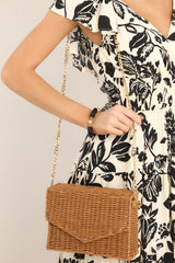 This tan bag features a removable chain strap, a wicker like design, and a magnetic snap closure.