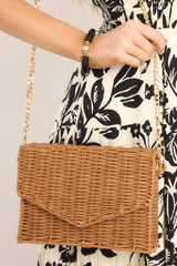 Close up view of this bag that features a removable chain strap, a wicker like design, and a magnetic snap closure.