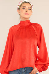Front view of this top that features a high neckline, balloon sleeves with buttons at the cuff, and an adjustable self tie around the neck.