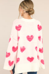 Back view of this sweater that features a crew neckline, a ribbed hem, a drop shoulder, wide arm sleeves and fun textured heart pattern.
