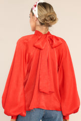 Back view of this top that features a high neckline, balloon sleeves with buttons at the cuff, an adjustable self tie around the neck, and a flowy fit.