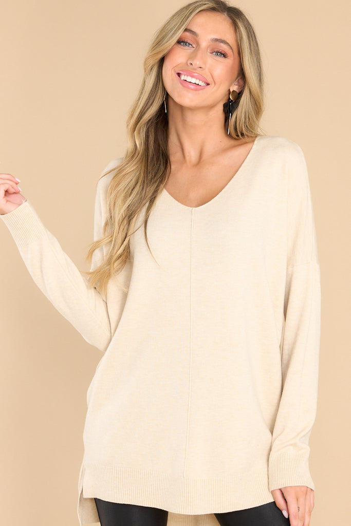 Front view of  this sweater that features a v neck and a high low hemline.