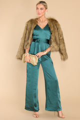 This emerald green jumpsuit features a v-neckline, crisscross straps on the back that are adjustable, a hidden zipper on the back, and a self tie strap around the waist. 