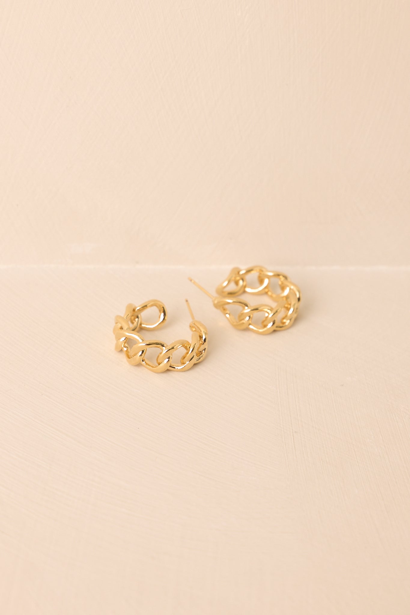 A close-up cropped shot highlighting the interlocking gold links and open hoop silhouette.