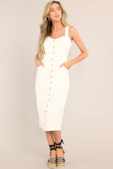This white dress features a sweetheart neckline, adjustable straps, a full button front, functional waist pockets, and functional back pockets.