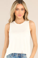 This ivory top features a round neckline, a wide arm sleeveless design, and a flowy, breathable fabric.