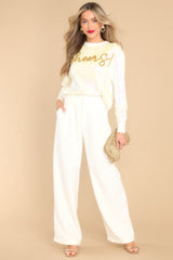 This white sweater features a crew neckline, iridescent sequins, textured writing, and cuffed long sleeves.