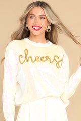 Front view of this sweater that features a crew neckline, iridescent sequins, textured writing, and cuffed long sleeves.
