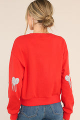 Back view of this sweatshirt that features silver rhinestone hearts, silver tassels, and ribbed hemming.