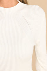 Close up view of this sweater that features a mock neck, long sleeves, ribbed detailing, a fitted silhouette, and a soft texture.