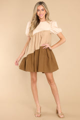 This beige dress features a crew neckline, a keyhole with a button closure on the back, elastic cuffed puffy sleeves, and pockets at the hips.