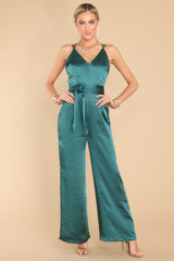 Full body view of this jumpsuit that features a v-neckline, crisscross straps on the back that are adjustable, a hidden zipper on the back, and a self tie strap around the waist. 