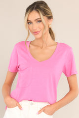 This pink tee features a v-neckline, a slouched breast pocket, a scooped hemline, and short sleeves.