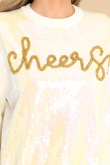 Close up view of this sweater that features a crew neckline, iridescent sequins, and gold textured writing that says 