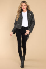 This black jacket features a double breasted collar, zipper closure, zippered pockets, attached waist belt with buckle closure, and zippered sleeves.