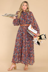 Full body view of this dress that features a mock neckline with adjustable self tie, slightly puffed sleeves, smocked cuffs, a full length liner, and an overall flowy silhouette.