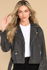 Front view of  this jacket that features a double breasted collar, zipper closure, zippered pockets, attached waist belt with buckle closure, and zippered sleeves.