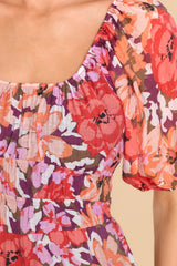 Close up view of this dress that features an elastic, round neckline, puff sleeves with elastic cuffs, a triple-banded elastic waistband, and a long, flowy skirt. 