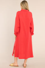 Back view of this dress that features a collared neckline, functional buttons down the front, a front pocket on the left side of the bust, long sleeves with a cuff secured by a functional button, and two slits up the bottom hemline ending just below the knee.