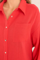 Close up view of this dress that features a collared neckline, functional buttons down the front, a front pocket on the left side of the bust, long sleeves with a cuff secured by a functional button, and two slits up the bottom hemline ending just below the knee.