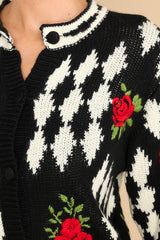 Close up view of this cardigan that features a scoop ribbed neckline, functional buttons all the way down, and embroidered roses.
