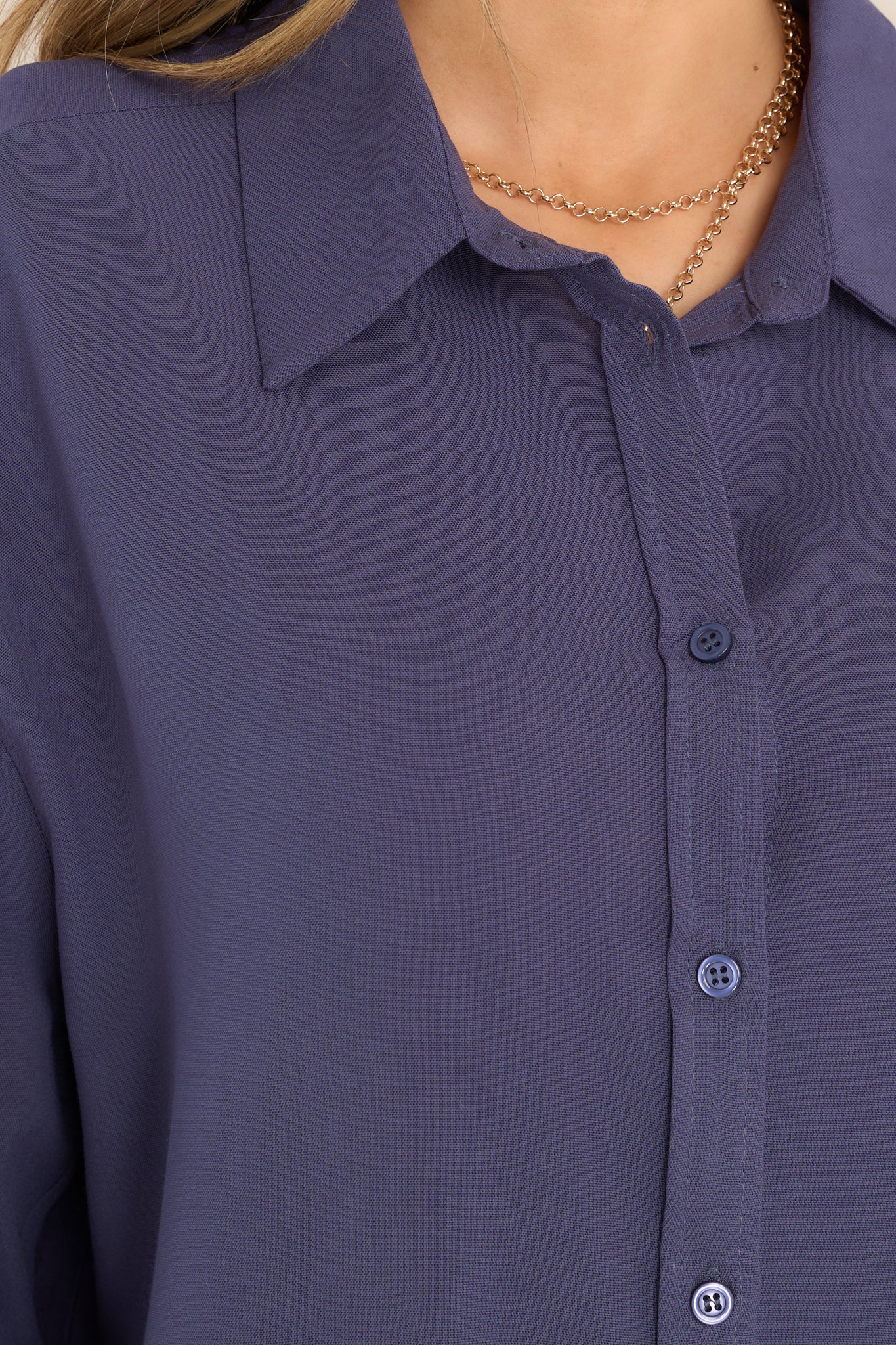 Close up view of this tunic that featuring a collared neckline, functional buttons down the front, long sleeves with buttoned cuffs, and a scoop bottom hem.
