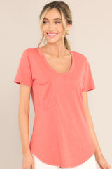 Full front view of this tee that features a v-neckline, a slouched breast pocket, a scooped hemline, and short sleeves.